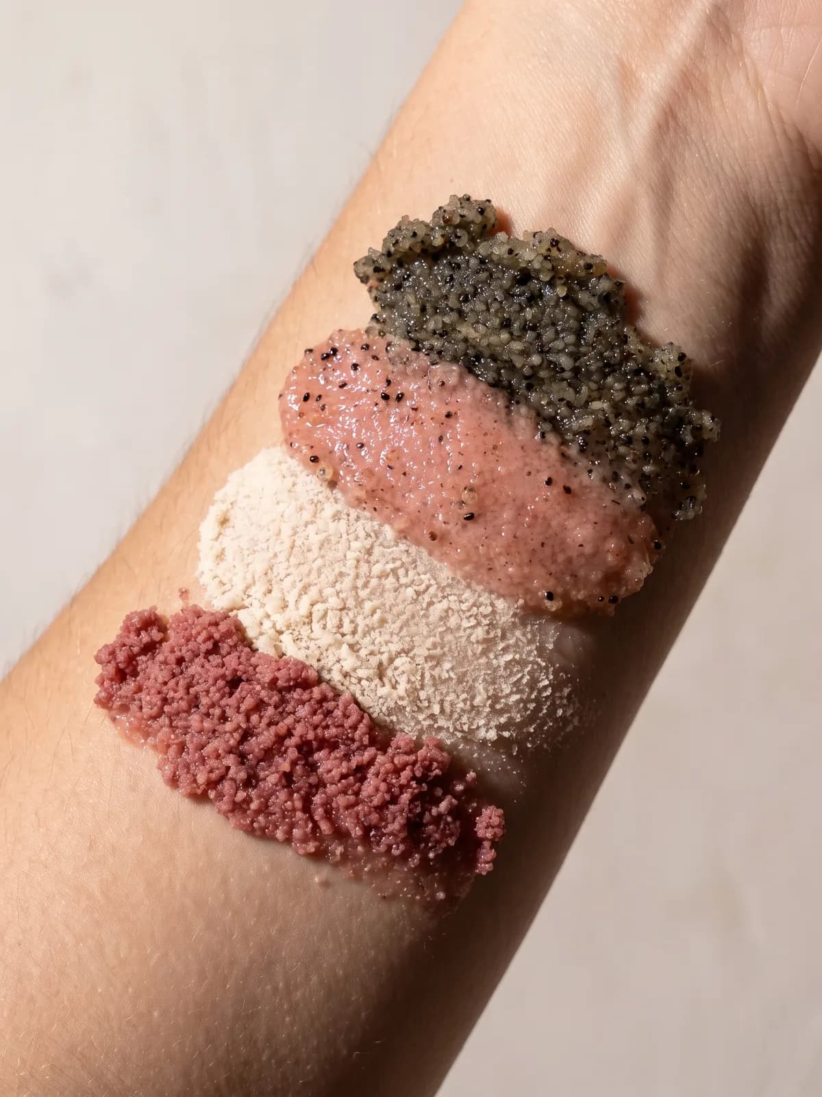 Four Bush & Salt body scrub textures swatched along a forearm, each a different colour